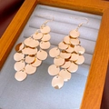 Detailed view of layered gold circular sequin drop earrings on gray velvet display - Gold