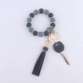 Détail du porte-clés en silicone perlé avec pompons gris et anneaux dorés strass - Gris Foncé