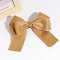 Detail of a large ginger yellow satin bow hair clip with fine edge stitching on white - Yellow