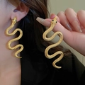 Gold-toned snake drop earrings with green gemstone eyes worn by a model in a close-up view - 40# Emerald Accent Snake Long Earrings