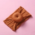 Macro detail of orange knit baby headband with a large decorative donut knot - Sunset Yellow