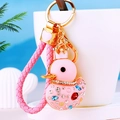 Pink duck keychain with rhinestones, golden crown, and matching woven strap on white cup - Pink Rope + Pink Duck
