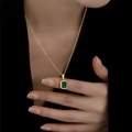 Elegante gouden ketting met rechthoekige smaragden hanger bij model op zwarte achtergrond - Smaragd Ketting