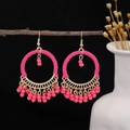 Detail of rose pink boho hoop earrings with hand-woven beads hanging on a branch - Pink