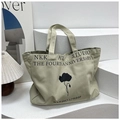 Dettaglio borsa tote in tela con stampa floreale e scritta NKK Art Studio - Grigio
