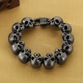 Detalle macro de pulsera de calaveras plateadas retro con cierre de cruz gótica punk - Negro Desgastado