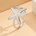 Adjustable silver starfish ring with realistic skin texture on a warm geometric background - J03317 / Silver