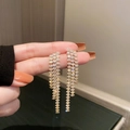 Detail of gold tassel drop earrings with shimmering zircon chains held in hand - Gold Tassel (Silver Pin)