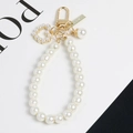 Dettaglio del portachiavi di perle a cuore con moschettone d'oro e targhetta - Stile Cuore di Perla