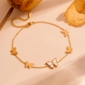 Detalle de la tobillera de mariposa en acero dorado con nácar blanco sobre superficie beige - Tobillera de Mariposa de Concha Dorada (L711)