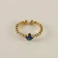 Bague ouverte dorée avec pierre précieuse bleue carrée et petits diamants sur beige - Bague bleue