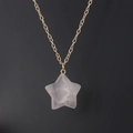 Detailed close-up of a pink crystal star pendant on a gold chain over black background - Gold Chain + Rose Quartz