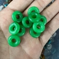 Handheld view of a green natural stone donut bead showing authentic texture and size - Malaysian Jade 1PC