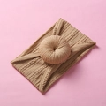 Detailed texture of beige knitted headband with donut knot on pink background - Light Coffee