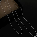 Detailed close-up of a glossy silver snake chain necklace draped over a black gift box - Two Sets Steel Color Round Snake Chain