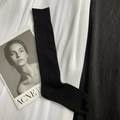 Classic black ribbed JK style high calf socks laid on pleated fabric and magazine - Calf Length Black