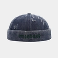 Dettaglio del berretto docker in denim blu con ricamo PROGRESS verde e bordi usurati - Regolabile / Blu navy