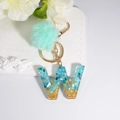 Green pom pom keychain with blue resin letter W pendant featuring gold flakes - Letter W