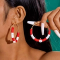 Close-up of red and white beaded hoop earrings with Santa charms on a female model - Red & White Clay Hoop with Santa