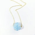 Detail of light blue irregular raw crystal pendant on a thin golden necklace chain - Apatite