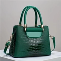Detailed view of dark green crocodile texture handbag with glossy finish and gold hardware - Green