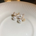 Makroaufnahme von Gold-Schleifen-Ohrsteckern mit Kristallen und einer weißen Perle - Silbernadel Gold Schleife Ohrstecker