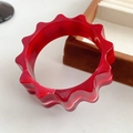 Detailed macro shot of red resin gear-shaped bangle on a brown velvet jewelry tray - Rose Red