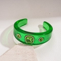 Detailed view of translucent green resin cuff bracelet with gold-rimmed emerald crystals - Green