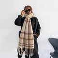 Close-up of a beige checkered mohair scarf with tassels paired with a stylish black coat - Beige