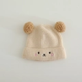 Détail du bonnet en tricot beige pour bébé avec pompons marrons et broderie ours - 1-3 Ans / Beige