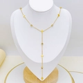Elegante collana a Y dorata con piccole croci e zirconi esposta su un busto bianco - Stile Croce