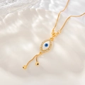 Detail der Evil Eye Halskette mit Goldkette und Zirkonia auf einem weißen Keramikteller - XL011-Emaille-Auge