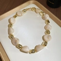Detail of acrylic beige irregular beads and golden metal spacers on a display tray - Necklace / White