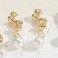 Macro shot of gold irregular metal earrings with white pearl pendants on white stone - S-Shaped Irregular Copper Style (ES2330-5)