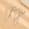 Detailaufnahme silberner Schleifenohrringe mit langen Quasten auf Steinhintergrund - Falten-Tassel-Schleife / Silber