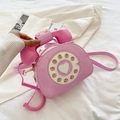 Close-up of pink patent leather phone-shaped crossbody bag with vintage dial and heart detail - Pink