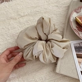 Close-up of beige puff fabric scrunchie held by hand over minimalist home aesthetic background - Off-white