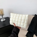Minimalist white quilted cosmetic bag with gold zipper detail held by a person - White