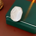Detail eines minimalistischen ovalen Harzrings mit weißem Stein auf Schmuckschatulle - Verstellbarer Ring / Silber-Weiß