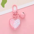 Pink heart keychain with glitter stars and bell on a soft pink and beige background - Pink
