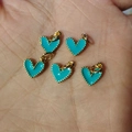 Five turquoise enamel heart charms with gold beaded edges held in hand for scale - Lake Blue