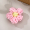 Handmade knitted pink flower hair clip accessory with yellow center on white desk - Pink
