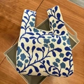Blue and white knitted tote bag with leaf patterns placed on a grey tray display - Blue Flower