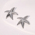 Minimalist silver starfish stud earrings in stainless steel on white stone background - Silver