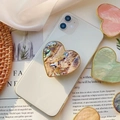 Dettaglio del supporto per telefono a cuore con texture in conchiglia e bordo oro - Impugnatura Cuore Oro / Conchiglia di Abalone Gialla