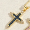 Macro shot of gold cross pendant featuring blue square zircons and white round crystals - Sapphire Blue
