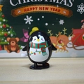 Wind-up penguin toy with Christmas scarf and festive lights on a wooden surface - Wind-up Oval Penguin with Scarf