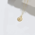 Collana dorata gotica con pendente a stella e rilievo solare su sfondo bianco minimalista - Sole