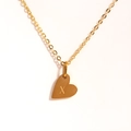 Détail du collier pendentif coeur doré avec une lettre X gravée sur du métal poli - Lettre X