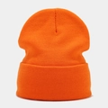 Close-up of bright orange knitted beanie featuring tight textured patterns and rolled cuff - Orange